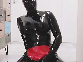 Rubber latex sissy with doll hood playing with anal dildo